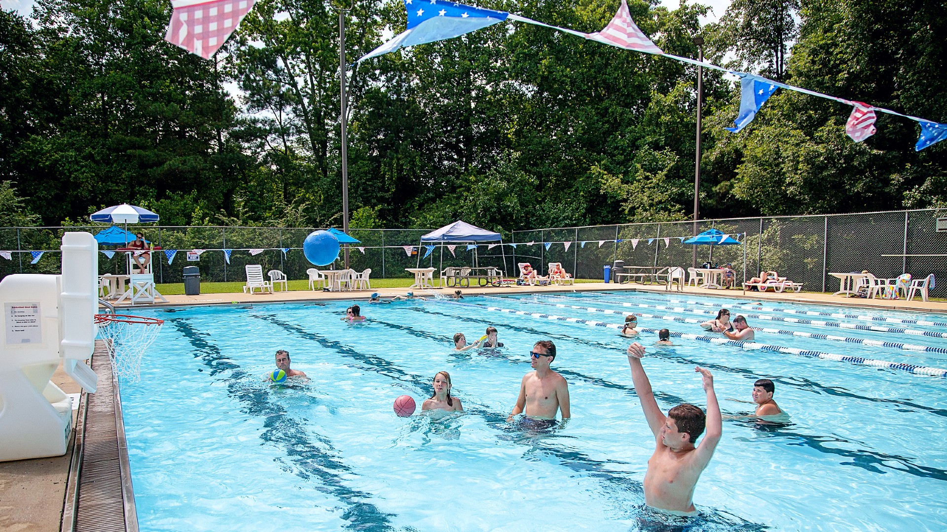 Family shooting hoops at an outdoor pool