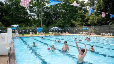 Family shooting hoops at an outdoor pool