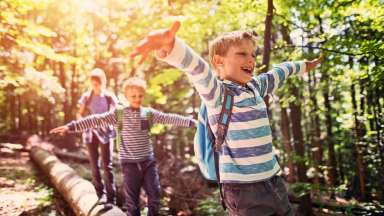 Kids walking over log in woods
