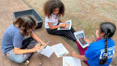 NEC students sit together working on an activity about turtles