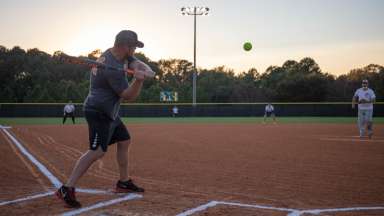 person swinging a baseball bat at a softball