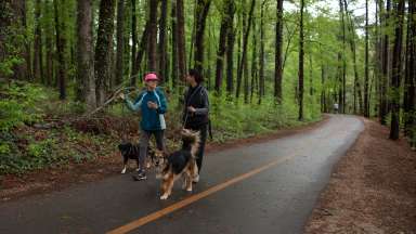 2 people walking on greenway trail with their dogs