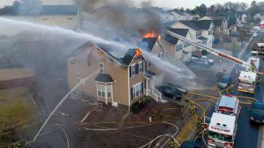 Home burning with fire trucks spraying home down with water