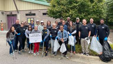 a group of smiling volunteers with litter grabbers and trash bags