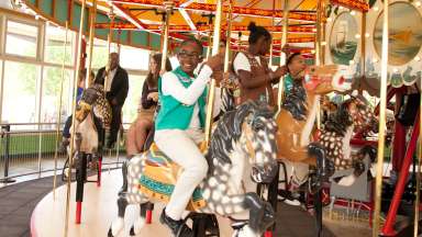 Little girl riding John Chavis Memorial Park historic carousel