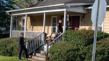 Three Raleigh officers stand on a porch talking with a resident.