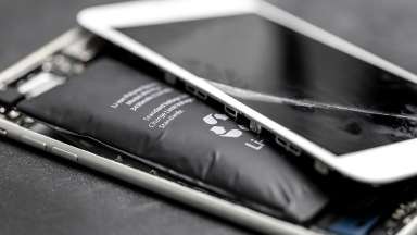an open mobile phone with a cracked screen and a lithium battery visible from inside the phone