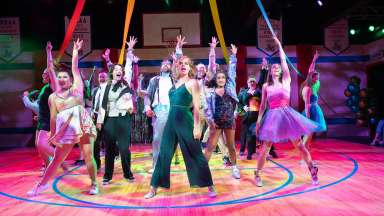 A group of dancers on a basketball court with their hands in the air