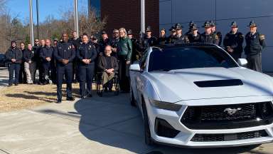 About 30 officials stand in front of the law enforcement training center by an unmarked police car after the press conference.