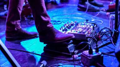 A guitarist stepping on an effects pedal