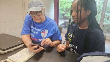 AAYD student helping community member with mobile device