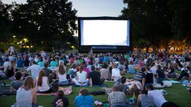an outdoor movie event with people sitting on a lawn