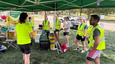 a group of volunteers standing under a tent wearing yellow safety vest