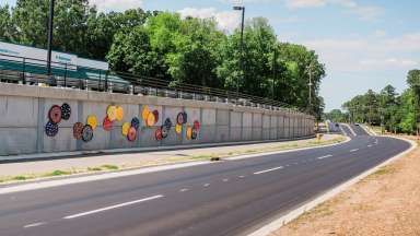 Colorful discs make up public art along a wall beside a road