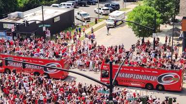 arial shot of parade with two buses and a large crowd