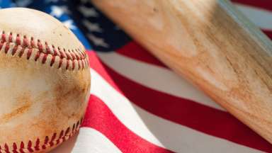 a baseball and bat with an American flag in the background