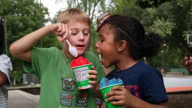 2 children eating snow cones in a park