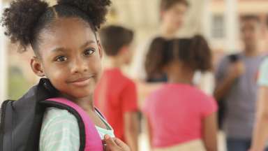 Child holding a bookbag on her back