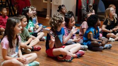 children sitting on the floor listening to a story while smiling