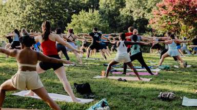 a group of people outside in a field doing a yoga move