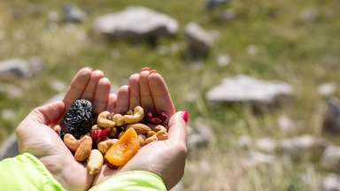 a close-up of hands holding trail mix outdoors