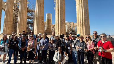 Group of active adults standing in front of travel scenery