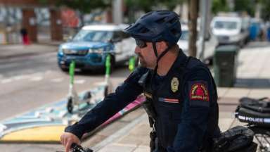 a police officer with a helmet on, and hand on a handlebar in an urban environment