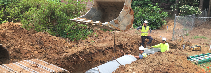 workers guiding backhoe equipment