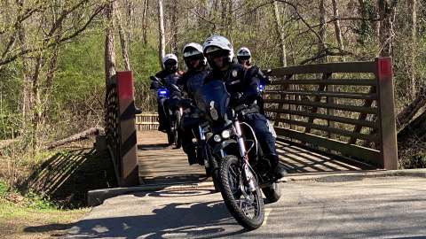 Four police officers riding dirt bikes on bridge