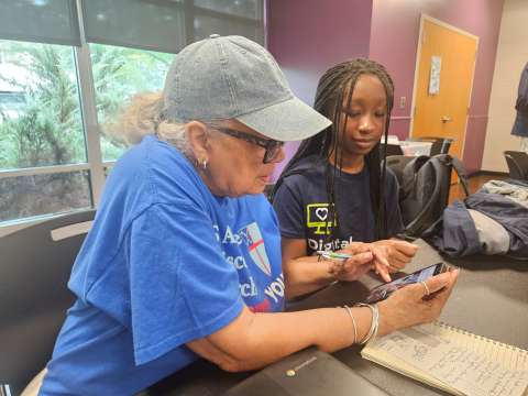 AAYD student helping community member with mobile device