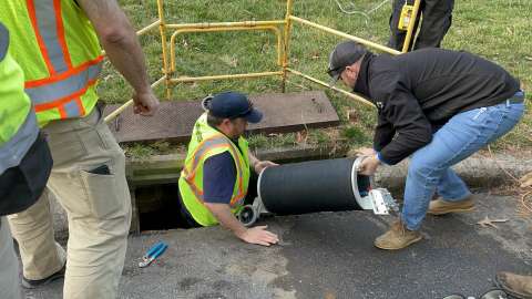 water worked in orange safety vest in storm drain replacing water pipe