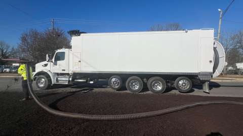 Worker spraying mulch on landscape