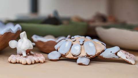 clay sculptures of a turtle and elephant, glazed and awaiting firing