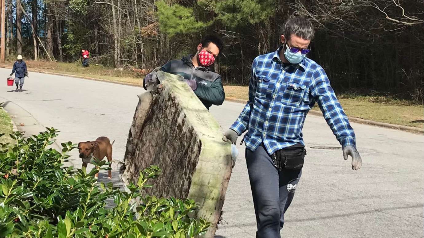 Two volunteers carrying a mattress that was cleaned up from a stream in Raleigh. 