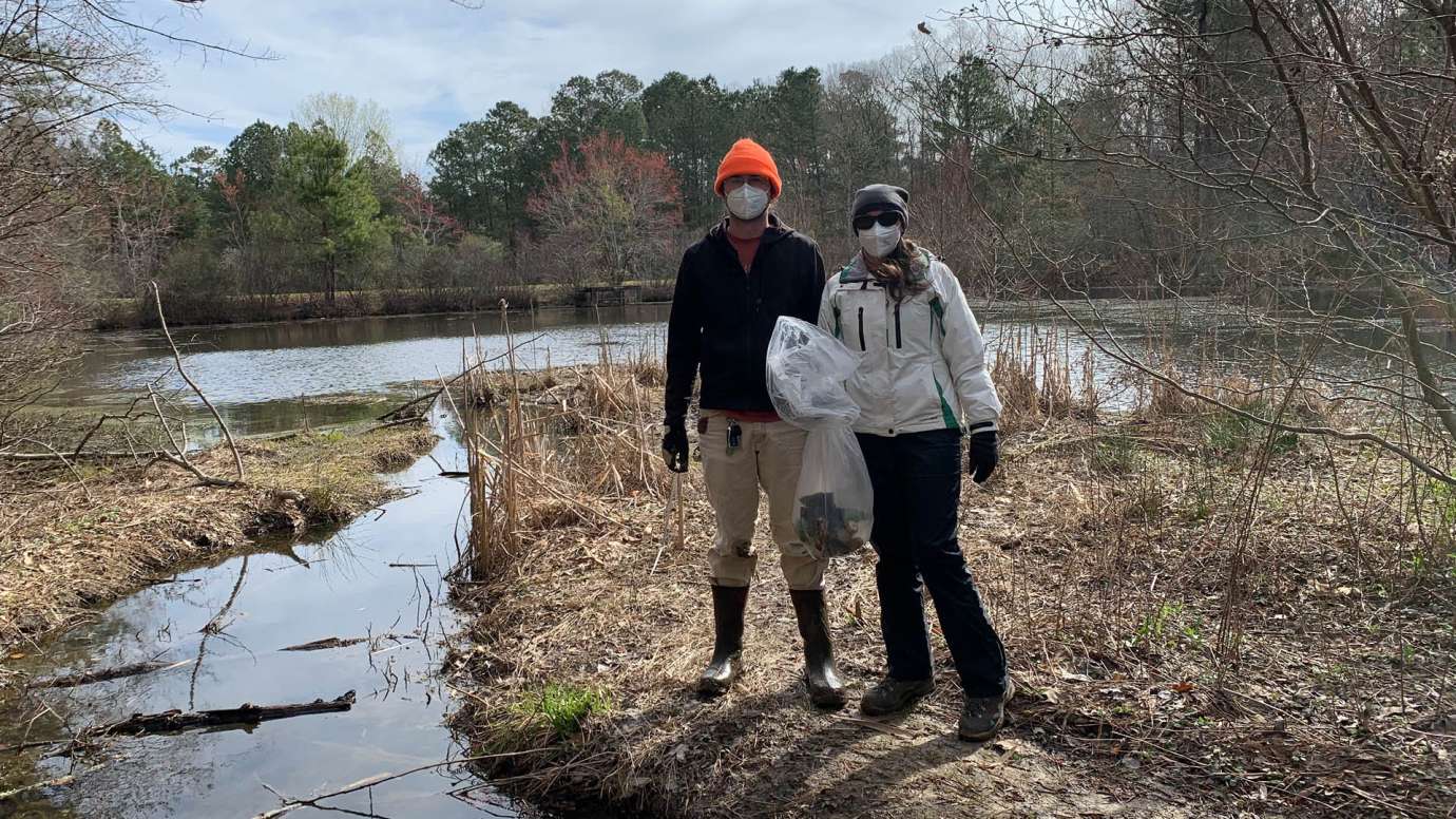 Two volunteers cleaning up a stream 