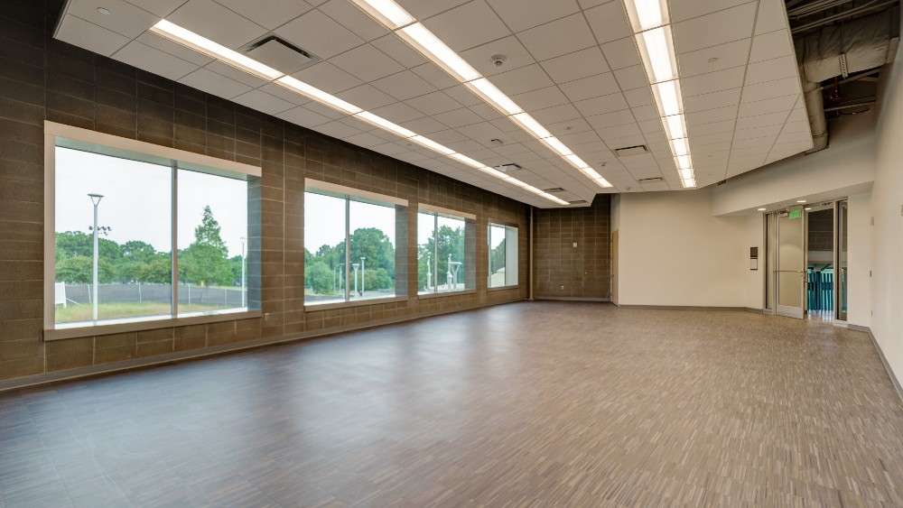 Interior multi purpose room with three large windows and vinyl flooring