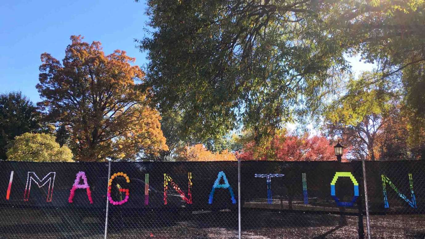 a construction fence is decorated with the word imagination in bright colors