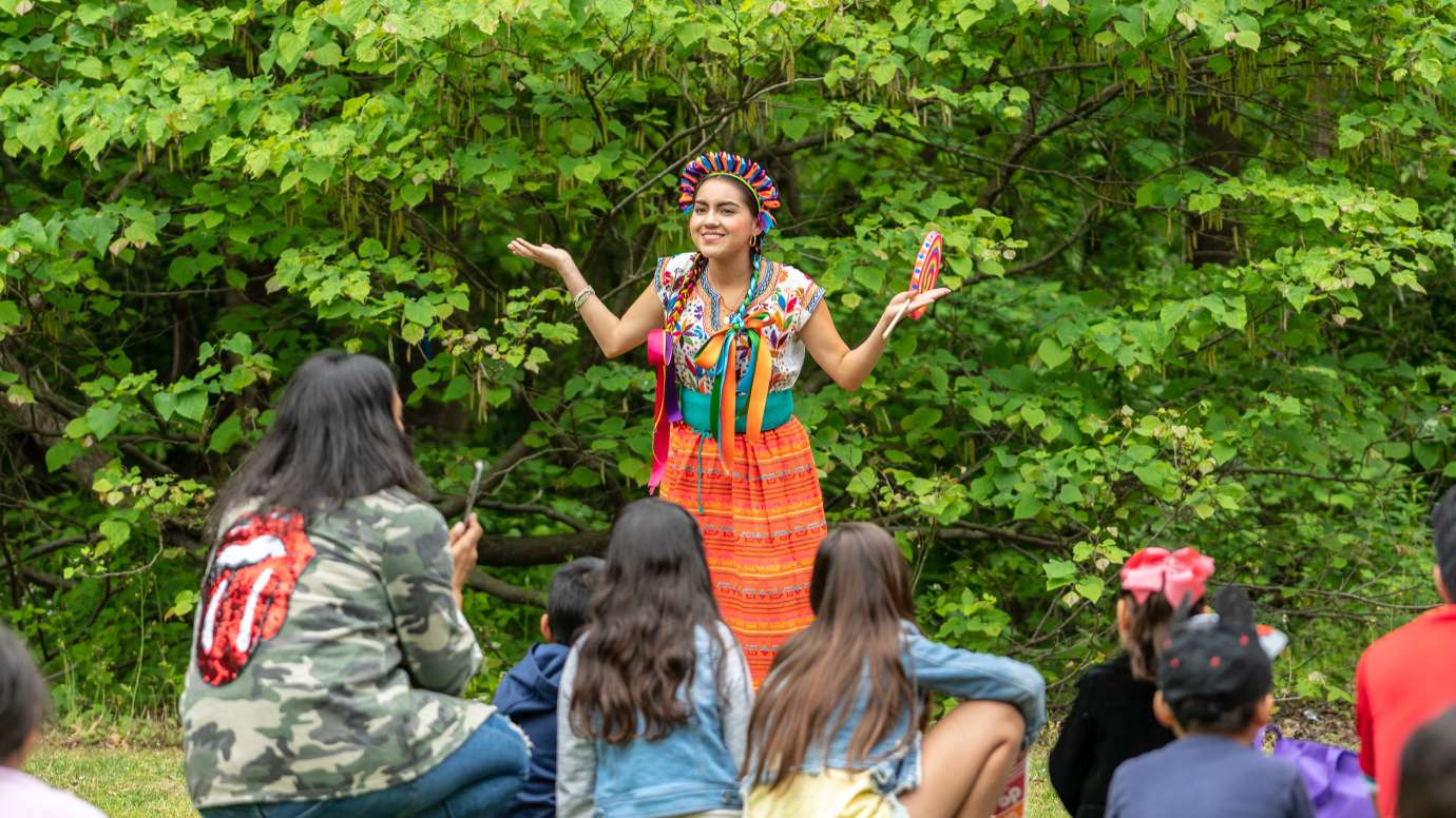 a person outdoors storytelling to children