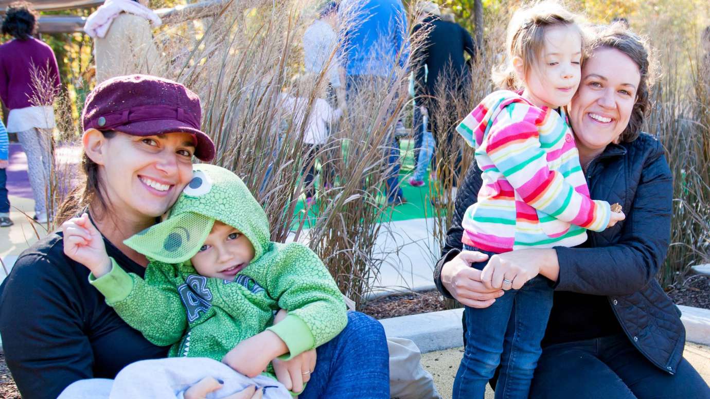 2 children with their guardians enjoying a park playground