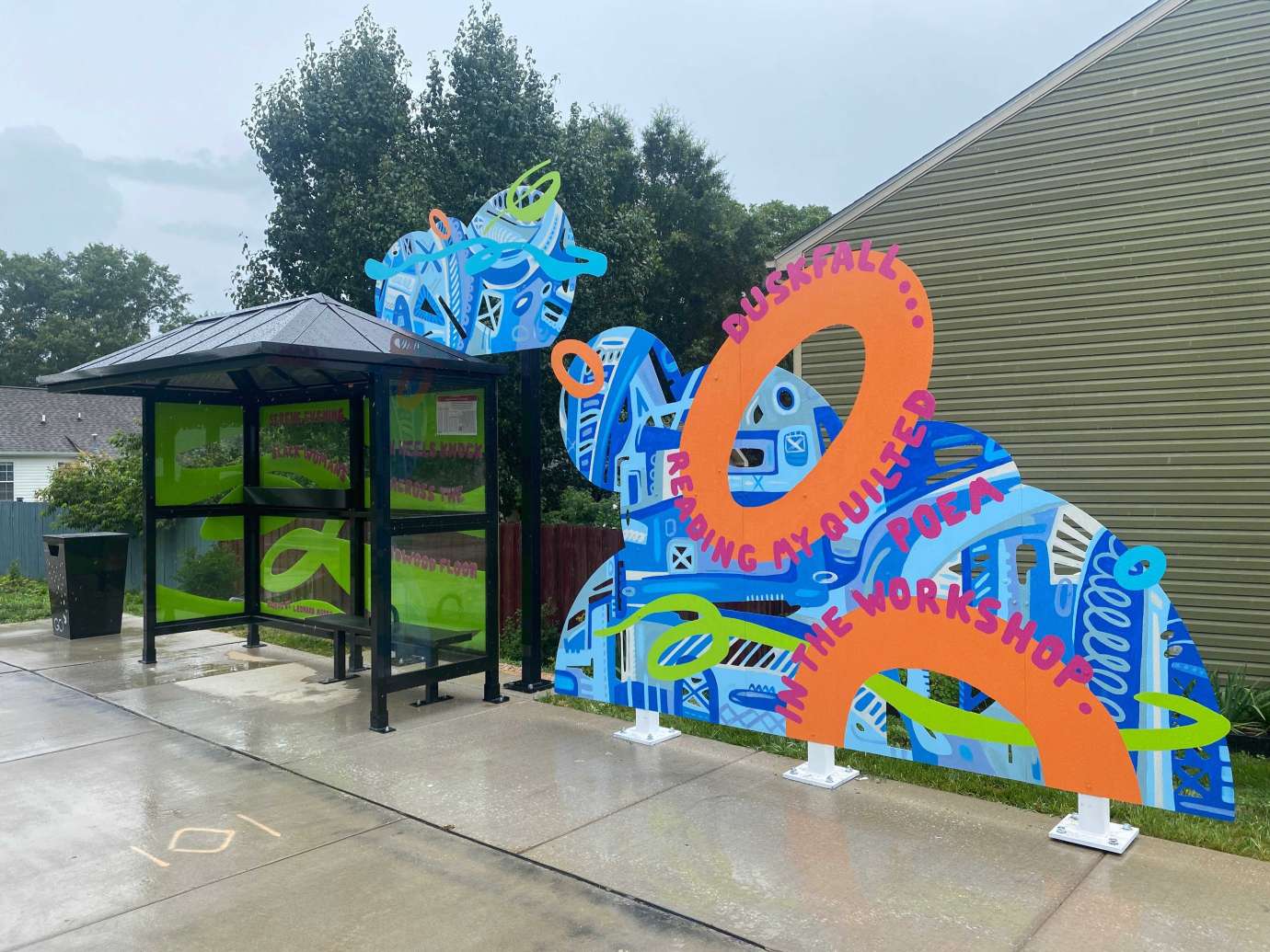 Colorful artwork installed behind and beside bus shelter on the south side of Poole Road