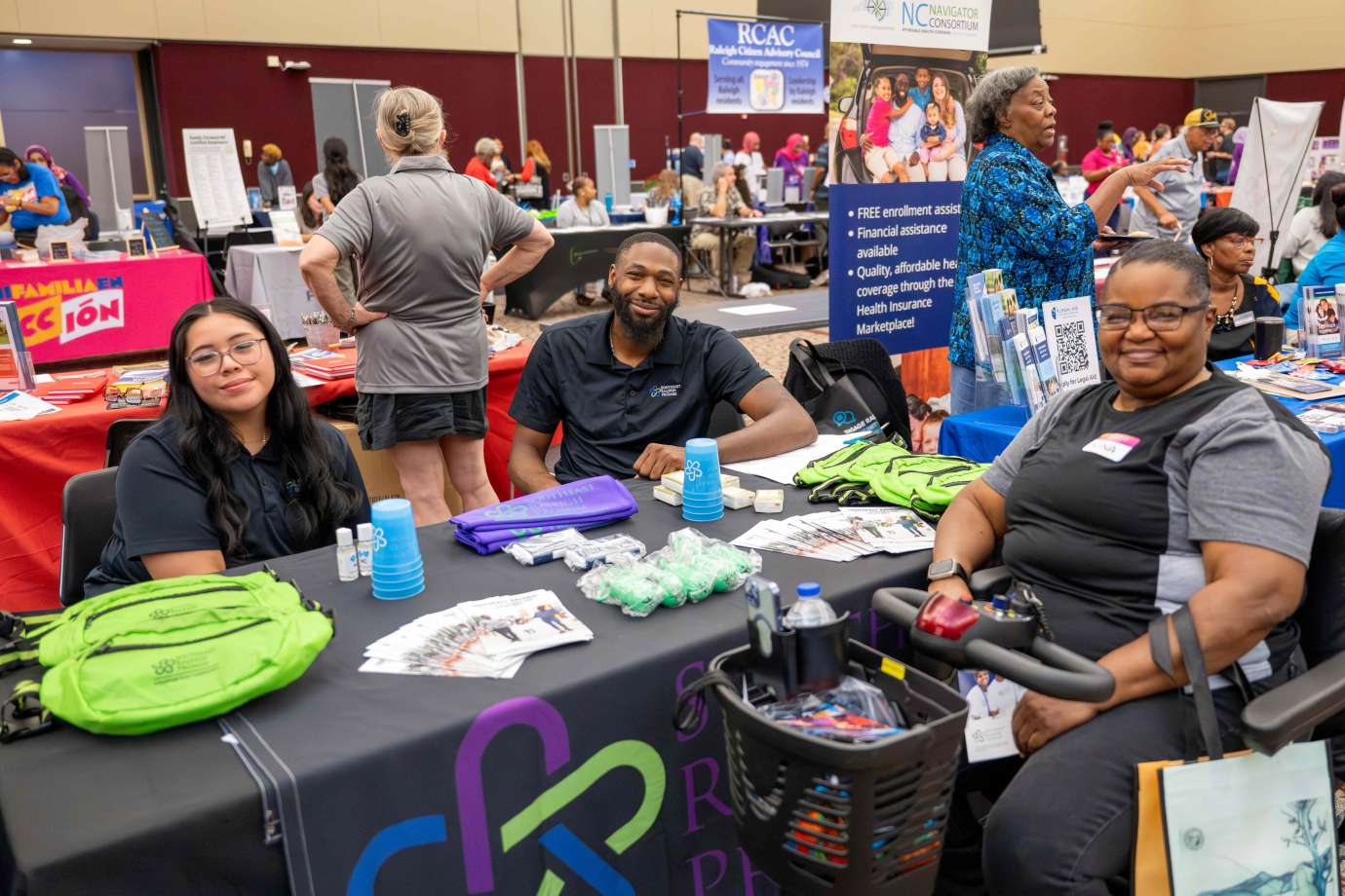 A woman with limited mobility engages with two people behind a table