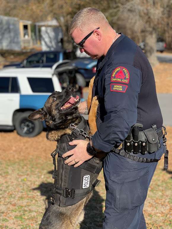 K-9 officer Hugo stands up on back legs with front paws on Officer Green's chest.Officer Green has hands on dog and both are looking at each other.
