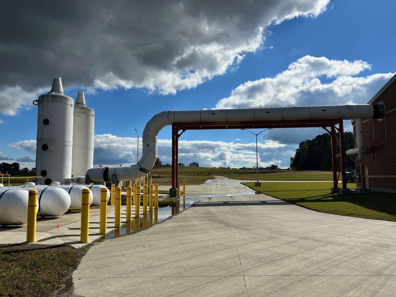 clouds and sun behind a large pipe and industrial setting