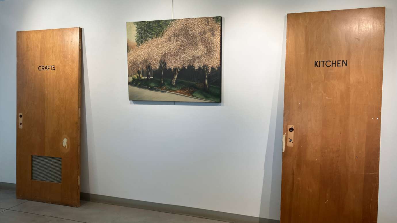 Two doors from the original Pullen Arts Center, one labeled “Crafts” and the other labeled “Kitchen,” alongside a landscape painting of cherry trees in bloom that was displayed at the original Pullen Arts Center