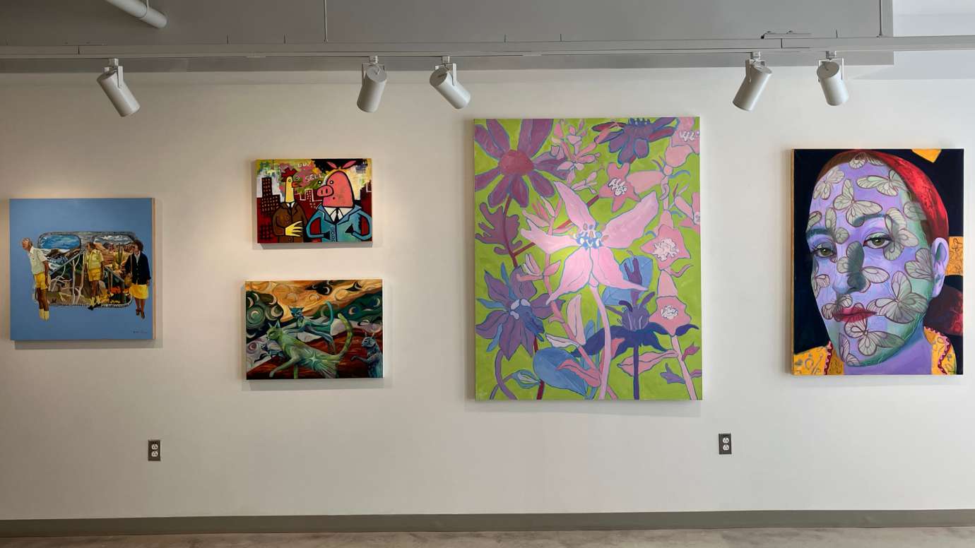 Five works installed in the gallery, from left to right: a painting of three figures in front of a surrealist landscape, a pop art style painting of a chicken and a pig in suits, a painting of three mystical cats, a large painting of pink and purple flowers, and an abstract portrait with butterflies on the face