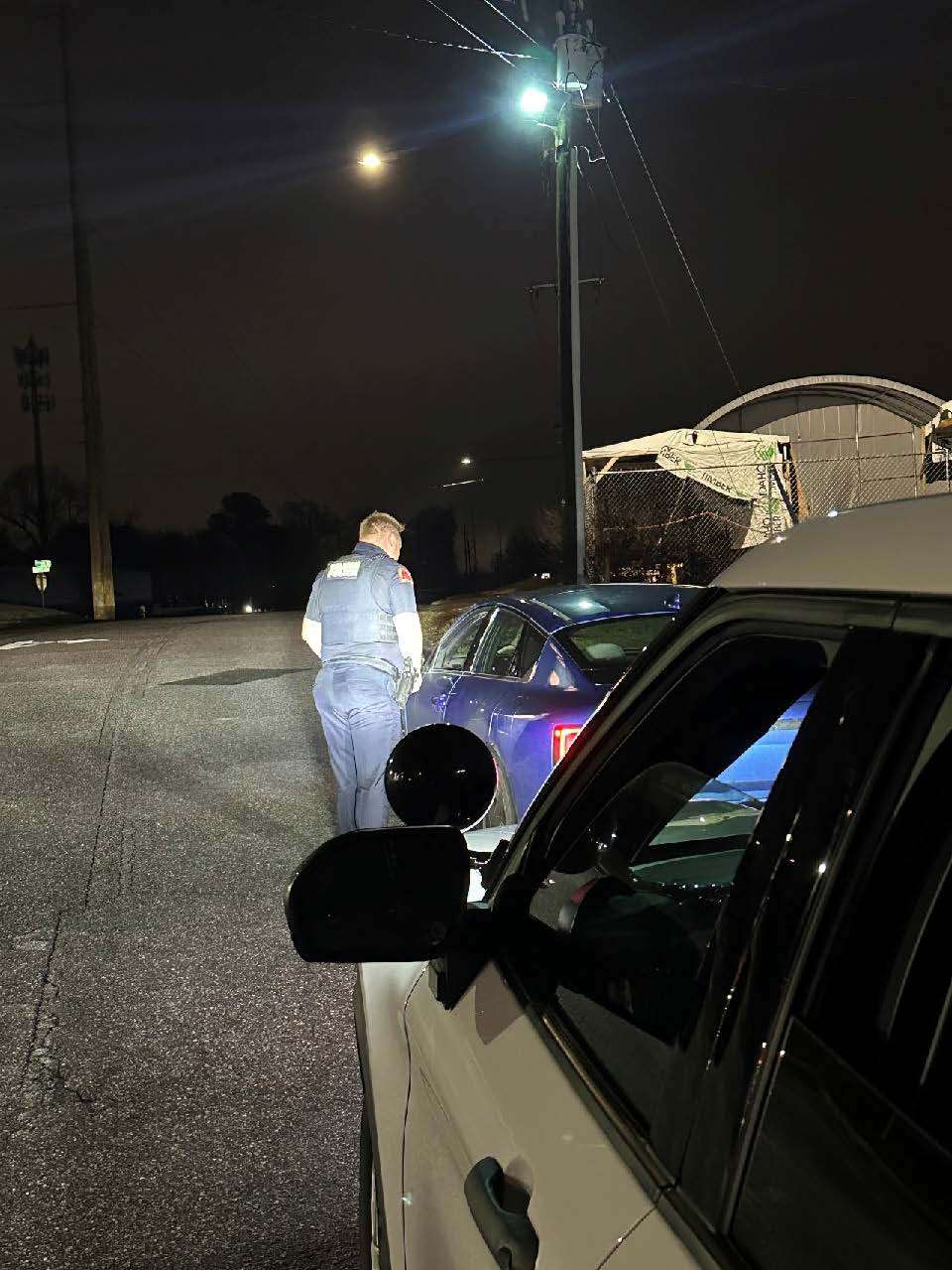 Police officer standing next to driver's car at night