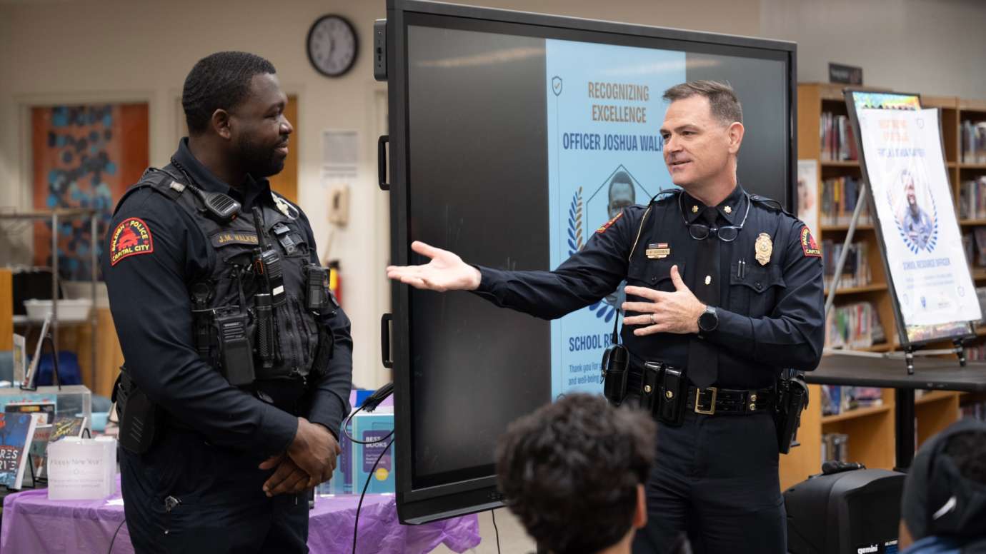Two police officers standing in front of screen