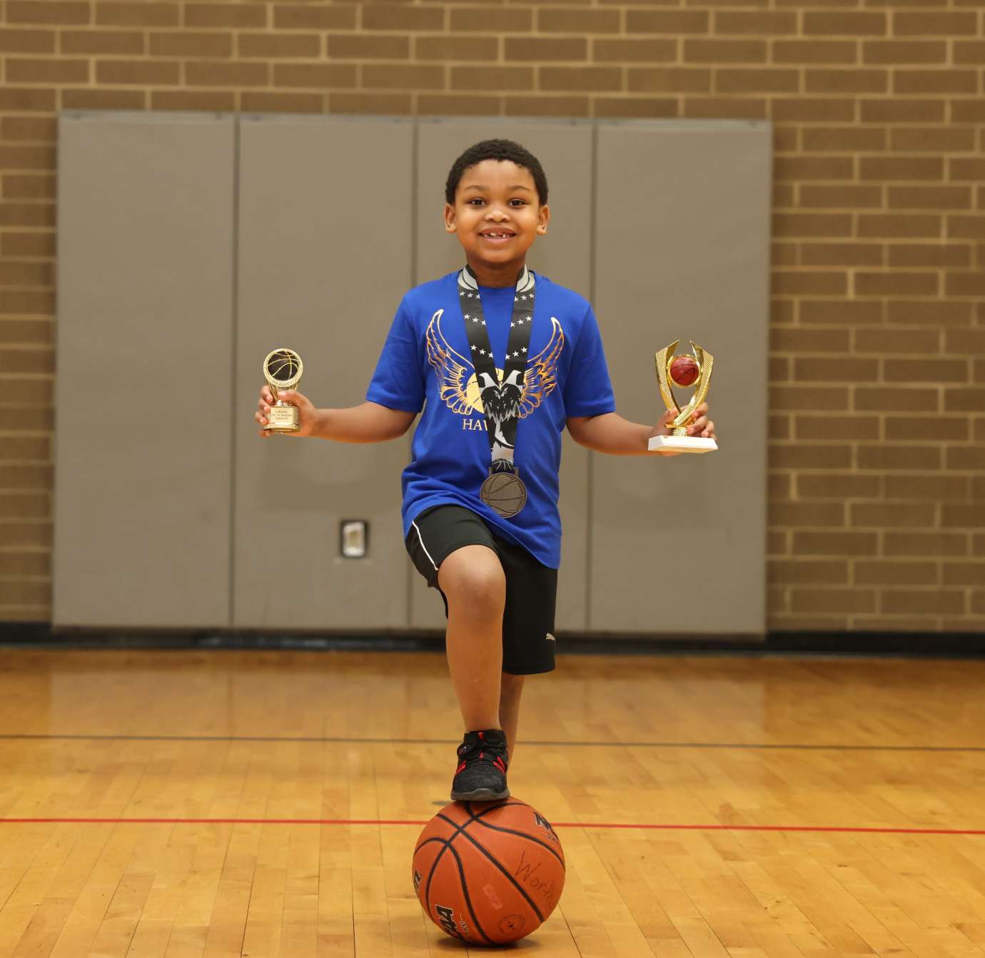 a boy holding two trophies and a medal around his neck