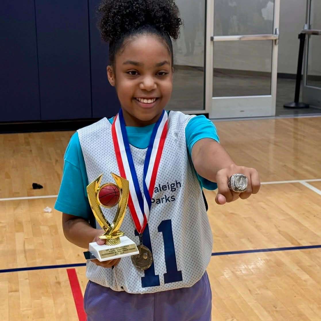 a child smiling with a trophy and ring for winning the sportsmanship award