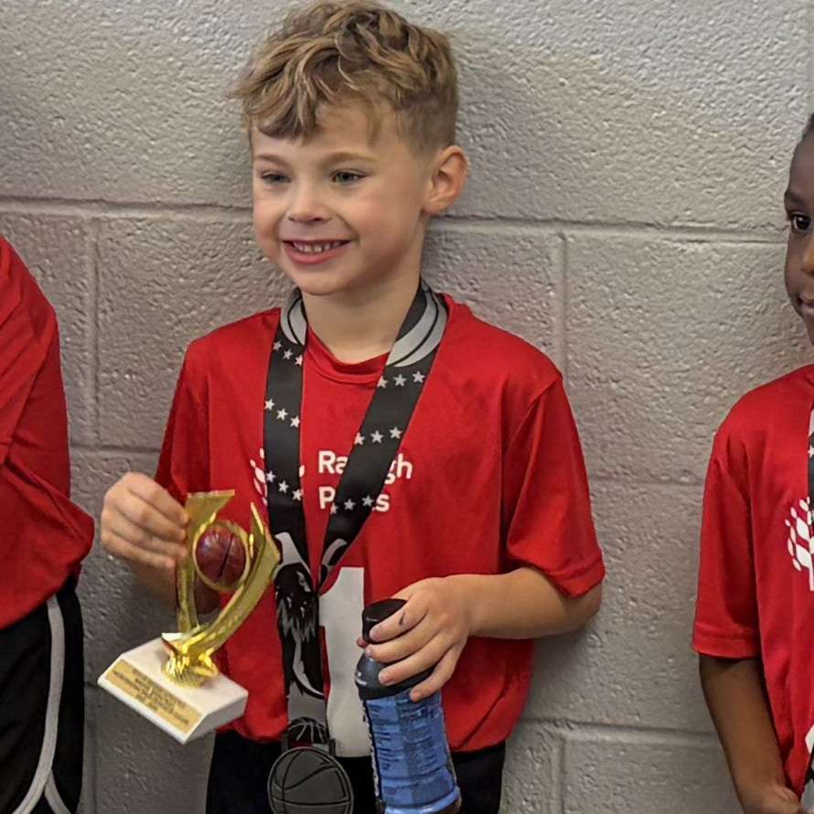a child smiling with a trophy for winning the sportsmanship award